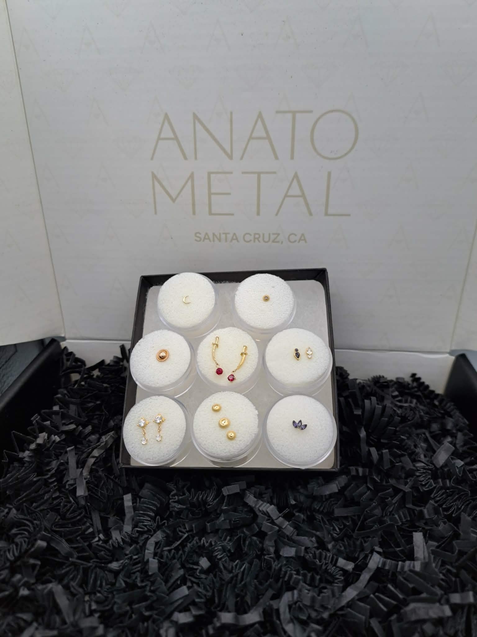 Curated Anatometal jewelry display featuring gold and gemstone piercing pieces