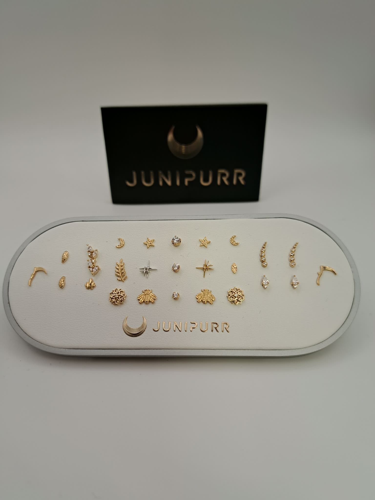 Junipurr gold and gemstone piercing jewelry arranged on a display tray